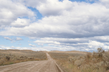 Winding dirt road among the hills with desert like landscape, grasslands and bush in Kamloops, British Columbia. Lac Du Bois