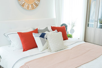 White bedroom with white and red pillows on it.