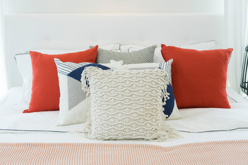 White bedroom with white and red pillows on it.