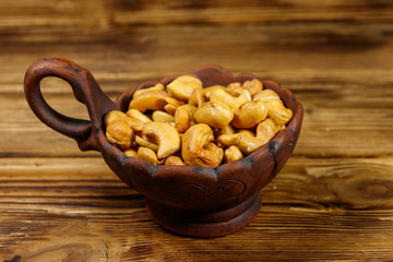 Ceramic bowl with roasted cashew nuts on a wooden table