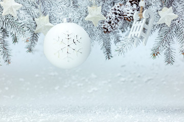 Fototapeta na wymiar snowy background with christmas tree branch decorated with white ball, wooden sledges and silver stars