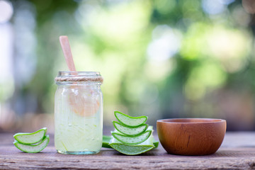 Fresh aloe vera stem slices and gel on wooden table, skin therapy concept