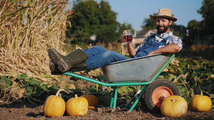 Farmer lying in a wheelbarrow resting and drink beer