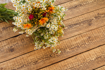 Bouquet of wildflowers on old wooden board.