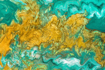 Fototapeta na wymiar Abstract yellow waves on green background with golden inclusions. Free flowing paint. Acrylic fluid art