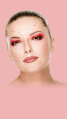 Beautiful woman with bright makeup and crystals on face, pink background. Aspect ratio and vertical...