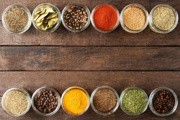 Various kinds of spices in bowls on wooden table with copyspace. Top view