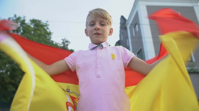Spanish football fan waving national flag, cheering team outside, championship