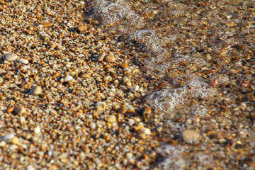 sea pebbles colored granite on the beach background stones. The shore of the beach with sand and pebbles washed by the waves of the sea.