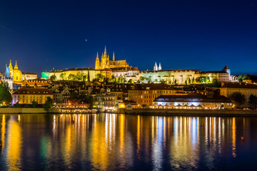 Fototapeta na wymiar Night View of the Lesser Town ( Mala Strana ) district and Prague castle, the largest coherent castle complex in the world, with the reflection on Vltava river.