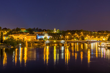 Naklejka premium Night view of beautiful building at the bank and the reflection on the Vltava River, view from the Charles bridge, one of the famous historic building in Prague, Czech.