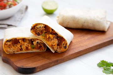 Homemade chorizo breakfast burritos on a rustic wooden board on a white wooden background, side view. Close-up.