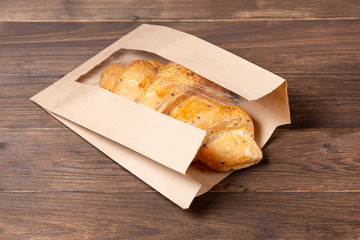 croissant in paper bag on wooden background. concept of continental breakfast and eco packaging, recycling of raw materials