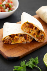 Homemade chorizo breakfast burritos on a black surface, side view. Closeup.