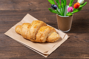 croissant in paper bag on wooden background. concept of continental breakfast and eco packaging, recycling of raw materials