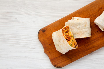 Homemade chorizo breakfast burritos on a rustic wooden board on a white wooden background, top view. Flat lay, overhead, top view. Copy space.