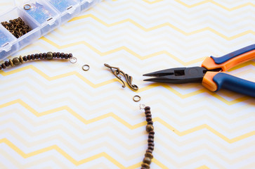 Pliers and unfinished boho necklace of wooden beads.
