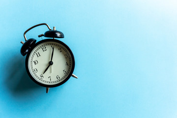 Vintage alarm clock on a blue clean background. Time management and time concept.