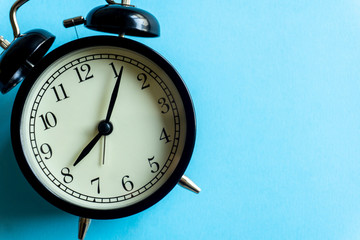 Vintage alarm clock on a blue clean background. Time management and time concept.