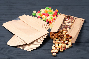 different nuts candied fruits and dried fruits on wooden background in eco package. concept of eco packages of recyclables