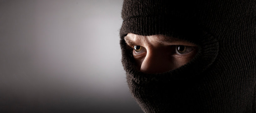 Angry Man In A Balaclava On A Dark Background.