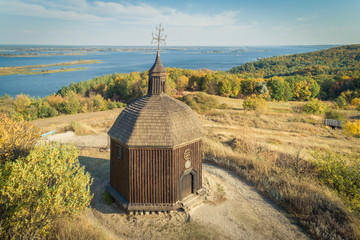 Autumn landscape of a small wooden church on a hill with a magnificent view on a  Dneper river in...