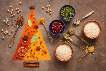 A variety of spices in the form of a Christmas tree, legumes, beans and cereals on a dark rustic background. New Year concept. Top view, flat lay.