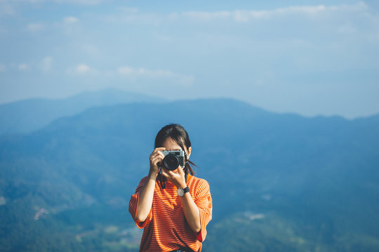 Hipster young girl with camera on peak mountain. Traveling alone concept.