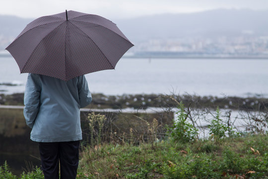 woman with umbrella walking along the coast