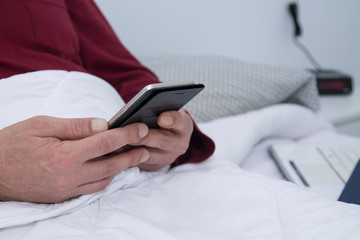 man lying in bed using his cellphone or smartphone