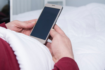 man lying in bed using his cellphone or smartphone