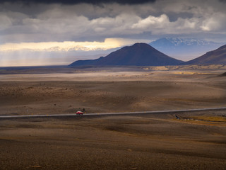 Red car on a road to the mountain in the Iceland