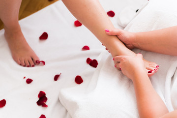 Obraz na płótnie Canvas Foot massage with rose petals