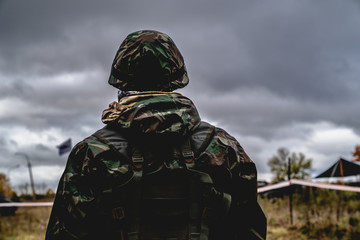 Soldier in the uniform and helmet at the battle field looking forward. Cloudy sky at the...
