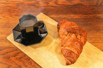 Classique petit déjeuner au bistro avec une tasse de café noir expresso et un croissant au beurre...