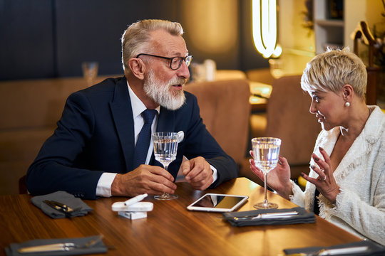 Man in elegant tuxedo and woman use tablet pc. Man holding tablet in hand. speak, chat with each other