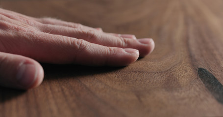 closeup man hand check oiled black walnut surface