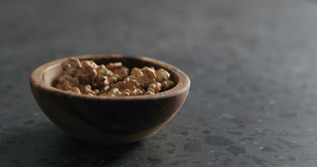 walnut kernels in wooden bowl on terrazzo countertop