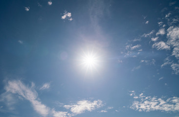 Nature background of clouds with clear blue sky background and sun with lens flare
