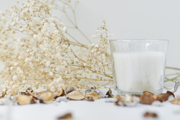 Candle with floral decor on a white table. Cozy and hygge background