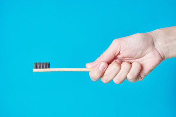 Wooden eco friendly bamboo toothbrush on a blue background. Dental care conept