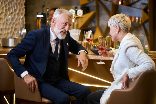 Caucasian man in tuxedo and woman in white blazer have conversation, smile and happy together in love. Background elegant expensive restaurant