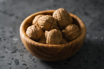 inshell walnuts in olive wood bowl on terrazzo countertop