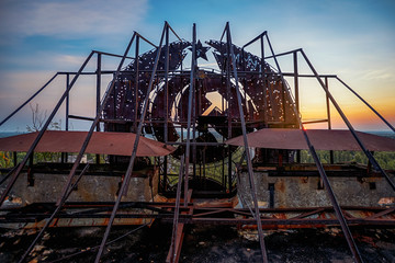 Soviet Union iron coat of arms in the dawn rays on the roof of a multi-storey building in an...