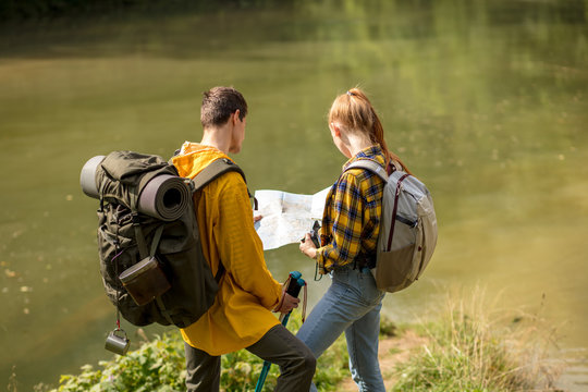 Couple backpackers standing near the lake, styding the map. back view photo. close up portrait, travle, tourism