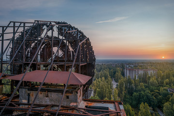 Soviet Union iron coat of arms in the dawn rays on the roof of a multi-storey building in an abandoned city of Pripyat after the Chernobyl disaster in April 1986