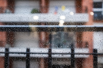 Many raindrops on a rainy indoor urban scene on a glass window
