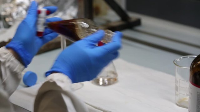 Scientist who is shaking an extract with organic solvents in a separating funnel