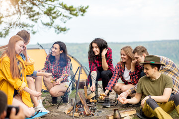 active young tourists enjoying preparing mushrooms outdoors. young people resting in the fresh air.