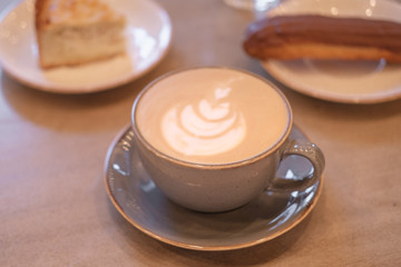 cup of cappuccino with a piece of cake and eclair